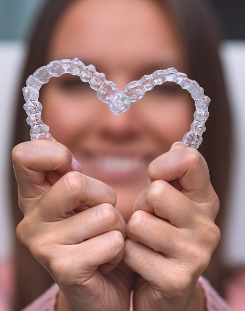 Dentist checking aligners on smiling patient's teeth
