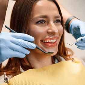 Dentist checking aligners on smiling patient's teeth