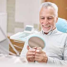 Man smiling at straight teeth in reflection