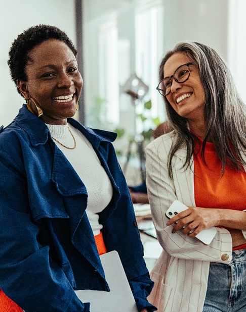 Two middle-aged women smiling confidently at work